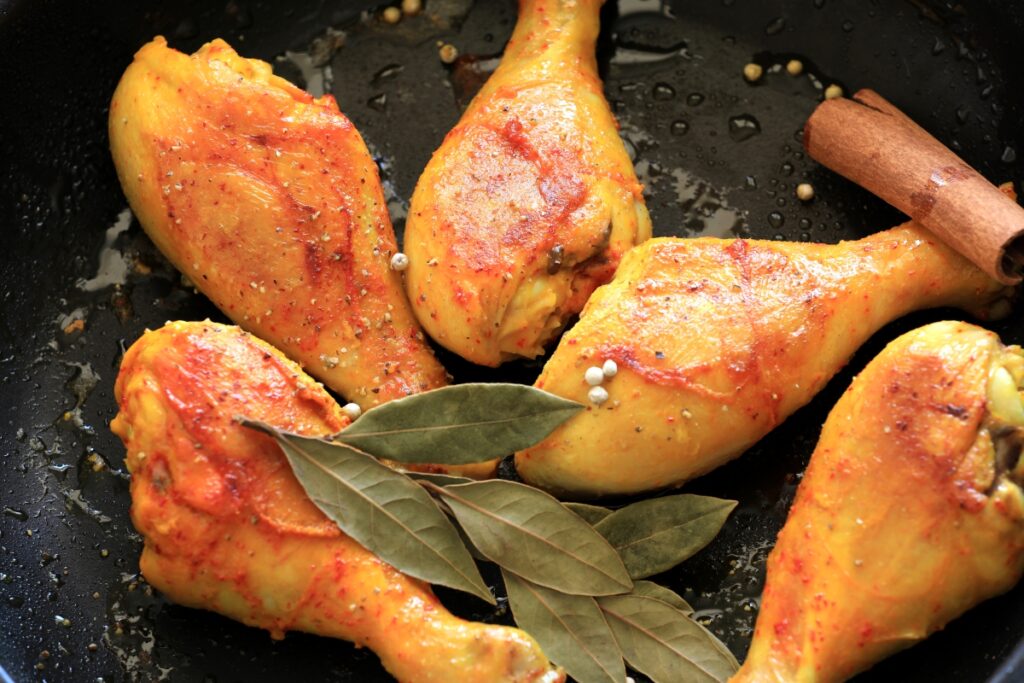 A pan filled with drumstick chicken seasoned with various spices and herbs, ready for cooking