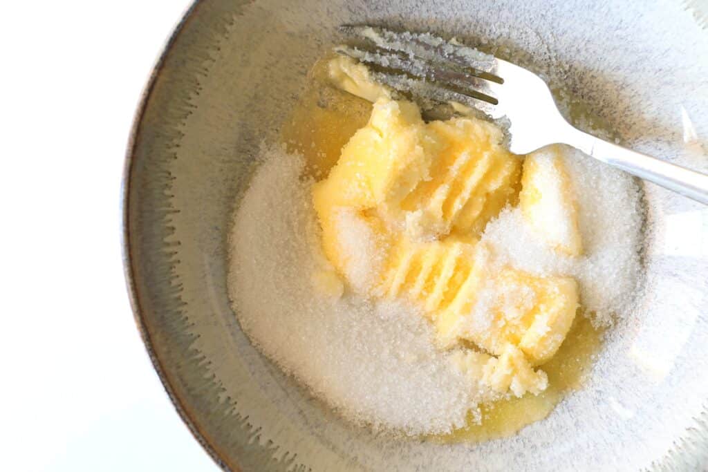 A fork resting in a bowl filled with sugar and butter