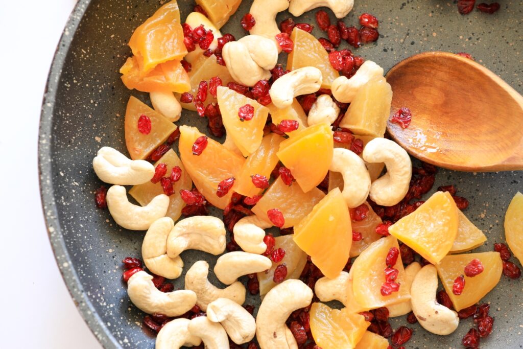 a pen filled with plums, cashews, barberries