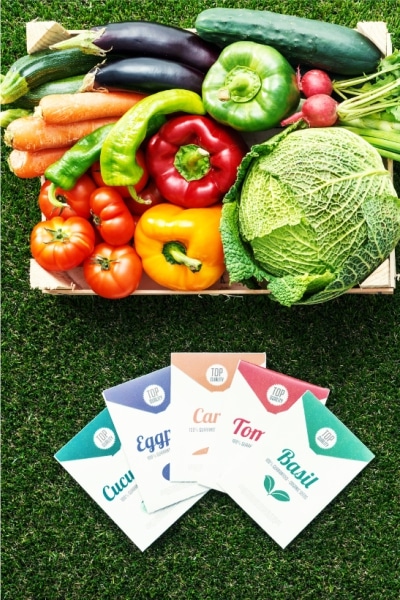 A box filled with assorted fresh vegetables alongside a card featuring an illustration of various vegetables.