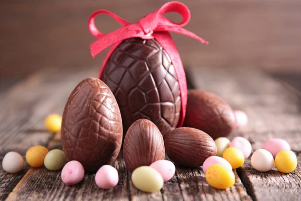 Colorful chocolate Easter eggs and assorted candies arranged on a rustic wooden table, creating a festive spring display.