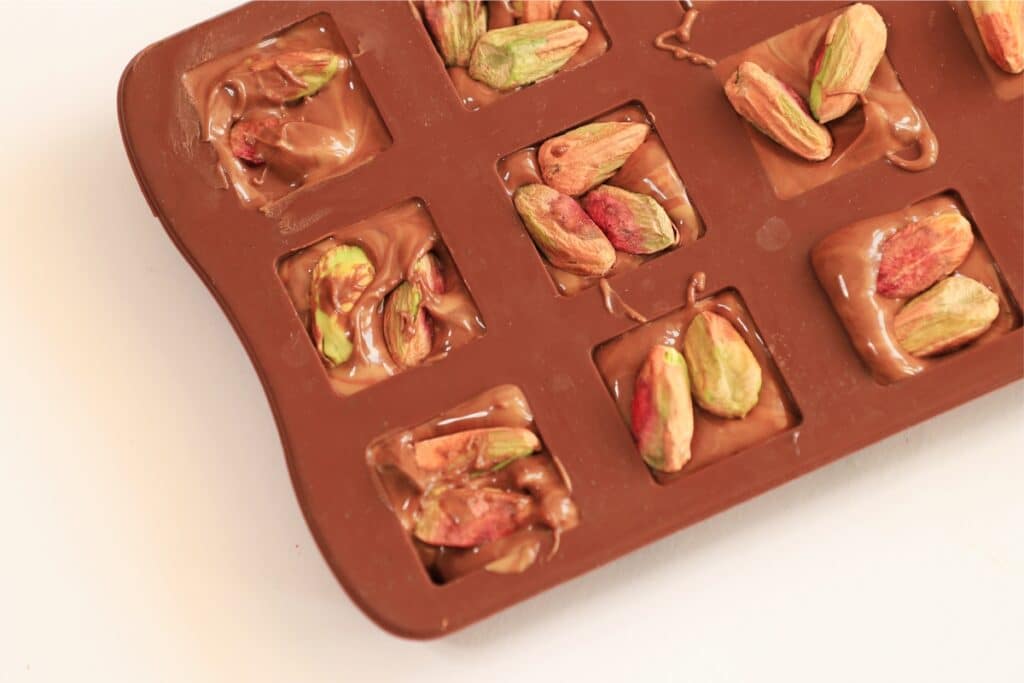 A tray filled with assorted chocolates and scattered pistachios, showcasing a delightful mix of textures and colors.