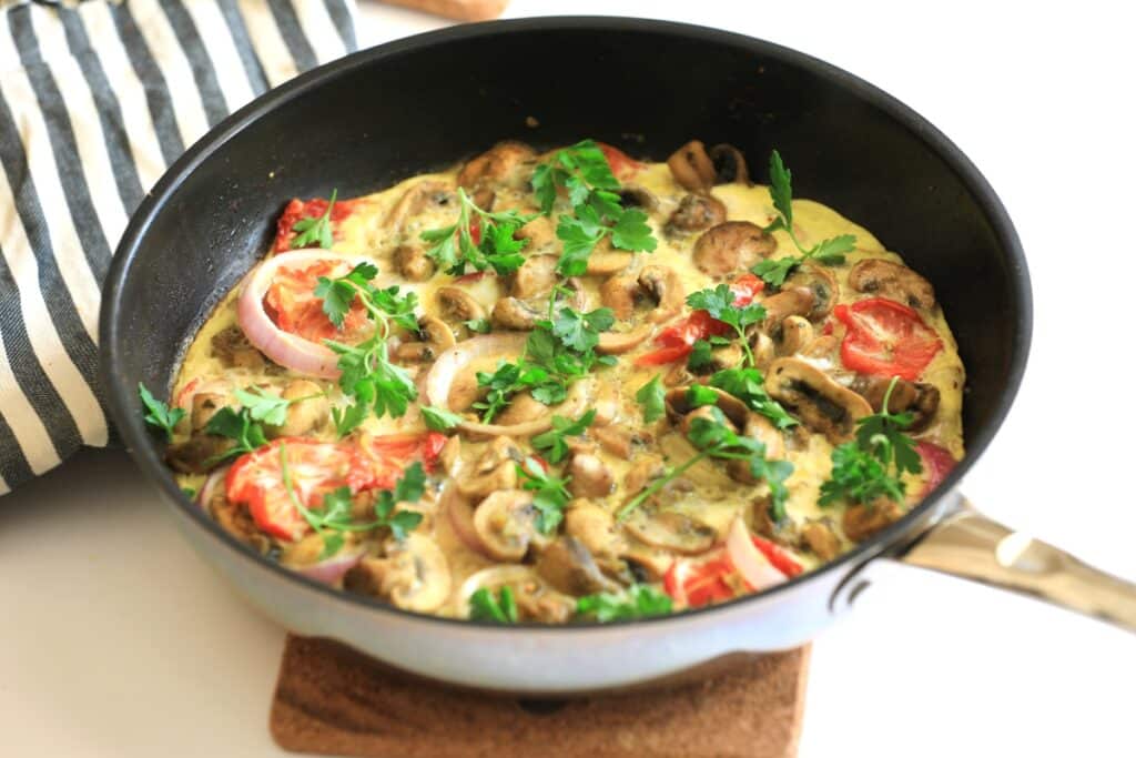 A pan filled with sautéed mushrooms and colorful mixed vegetables.
