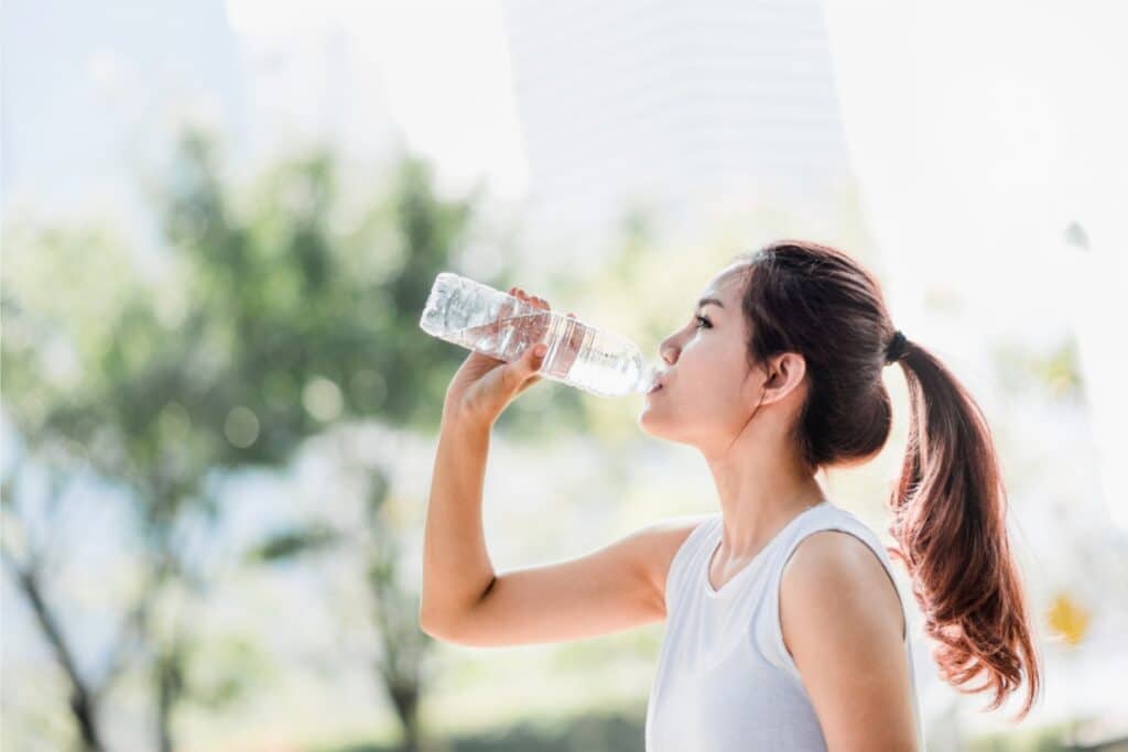 A woman taking a sip from a water bottle, looking refreshed and hydrated.