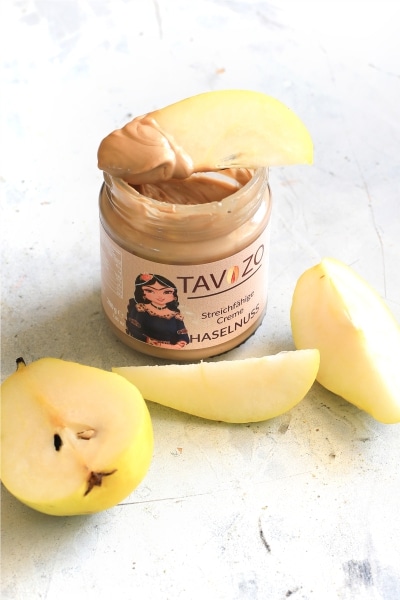 A jar of peanut butter topped with fresh apple slices, showcasing a healthy snack option.