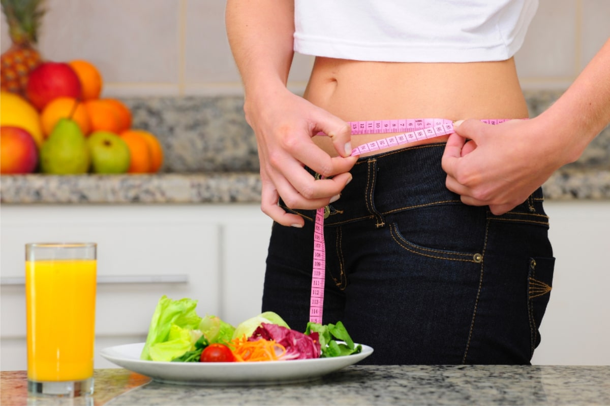 A woman measuring her waist with a measuring tape