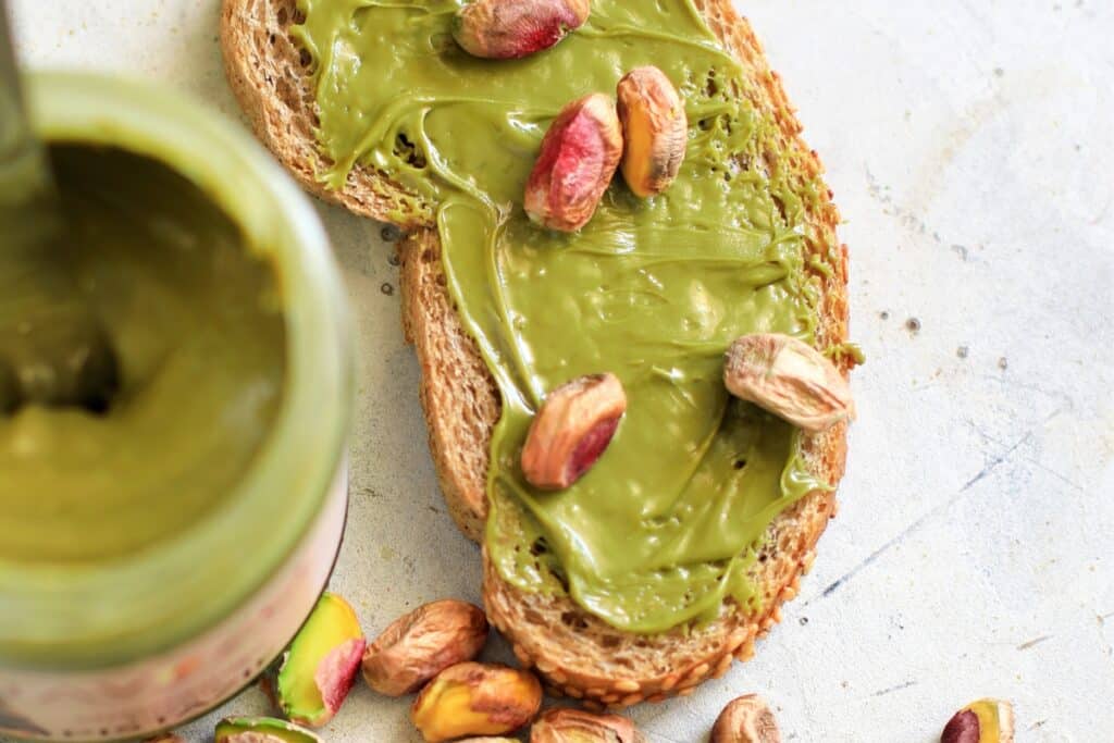 A slice of bread topped with a smooth layer of green pistachio spread.