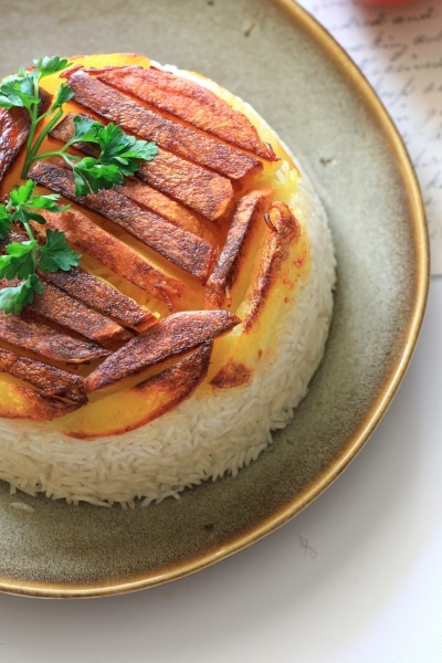 A plate of rice garnished with a succulent piece of meat, showcasing a simple yet appetizing meal presentation.