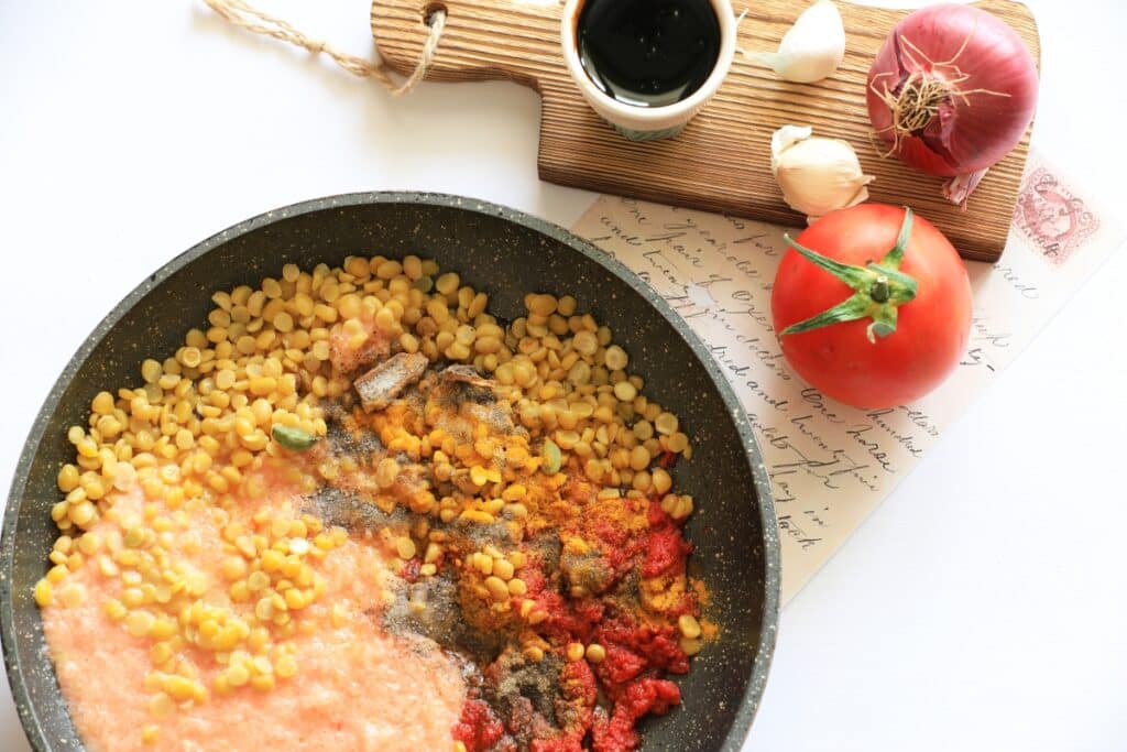 A pan filled with sautéed corn, diced tomatoes, and chopped onions, showcasing a colorful and fresh vegetable medley.