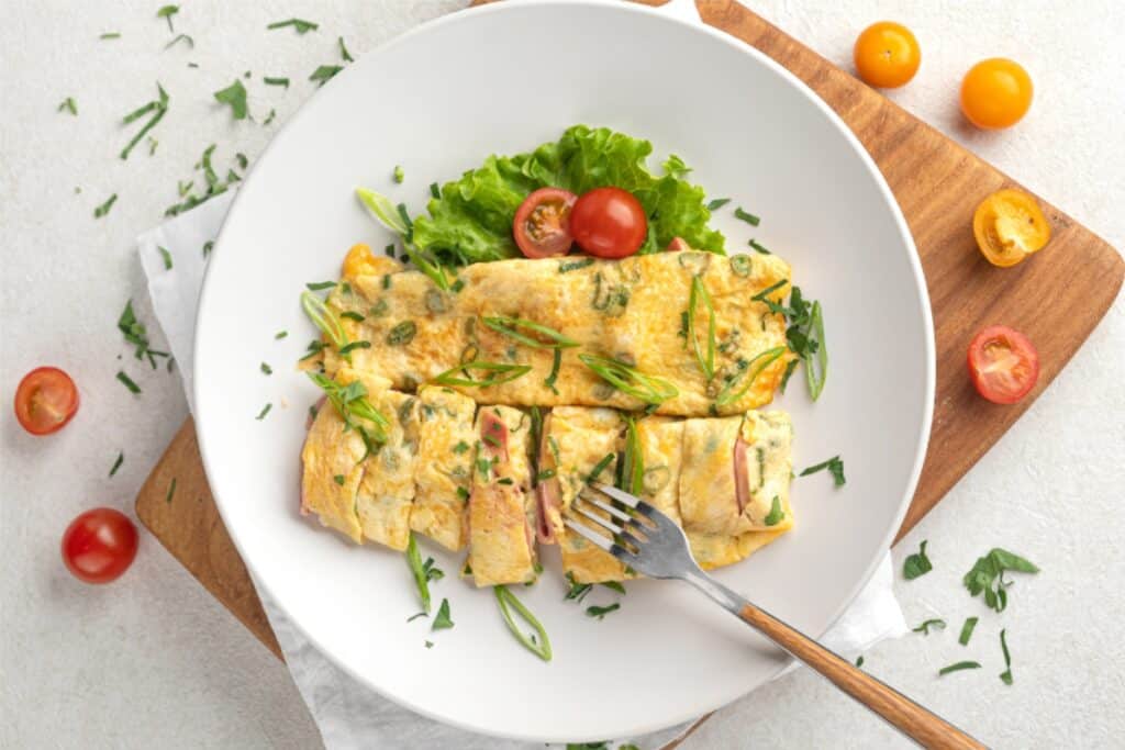 A plate featuring a fluffy omelet accompanied by a colorful assortment of fresh vegetables.