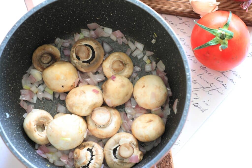 A skillet filled with sautéed mushrooms and onions, showcasing a golden-brown color and a savory aroma.