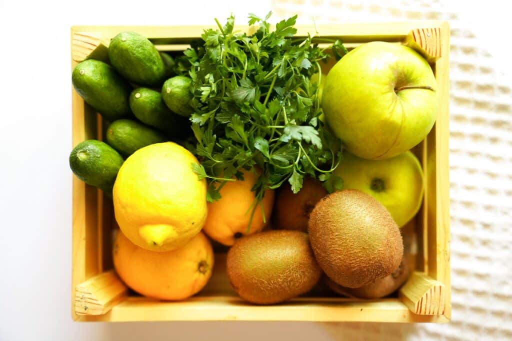 A wooden crate overflowing with a colorful assortment of fresh fruits and vegetables.