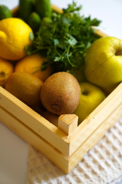 A wooden crate overflowing with a colorful assortment of fresh fruits and vegetables.